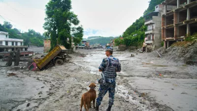 A policeman with a sniffer dog looks at the damage in the aftermath of flash floods in Devighat in the Nuwakot district in Nepal, Thursday, Aug 27, 2026. (AP Photo/Niranjan Shrestha)