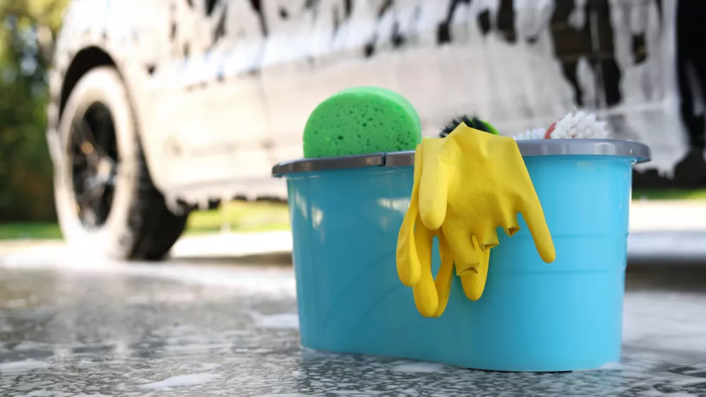 Car cleaning supplies and auto covered with foam outdoors