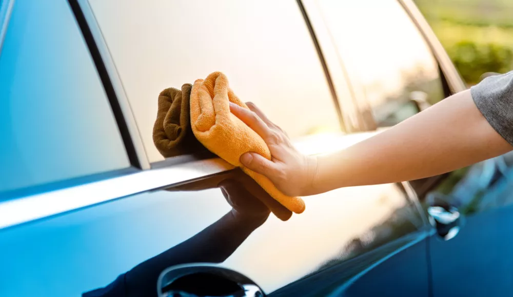 Woman hand cleaning car with a cloth