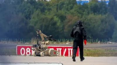 FILE PHOTO: A police officer in protective clothing walks next to an explosive-disarming robot (EOD) at Leipzig/Halle Airport in Schkeuditz, Germany, August 5, 2026, after the police said explosives experts examined a drone found near a runway, and after a DHL cargo aircraft hit an unknown object as it was climbing away from the airport overnight, prompting an unscheduled landing in Hanover, according to a source familiar with the incident. REUTERS/Axel Schmidt/File Photo
