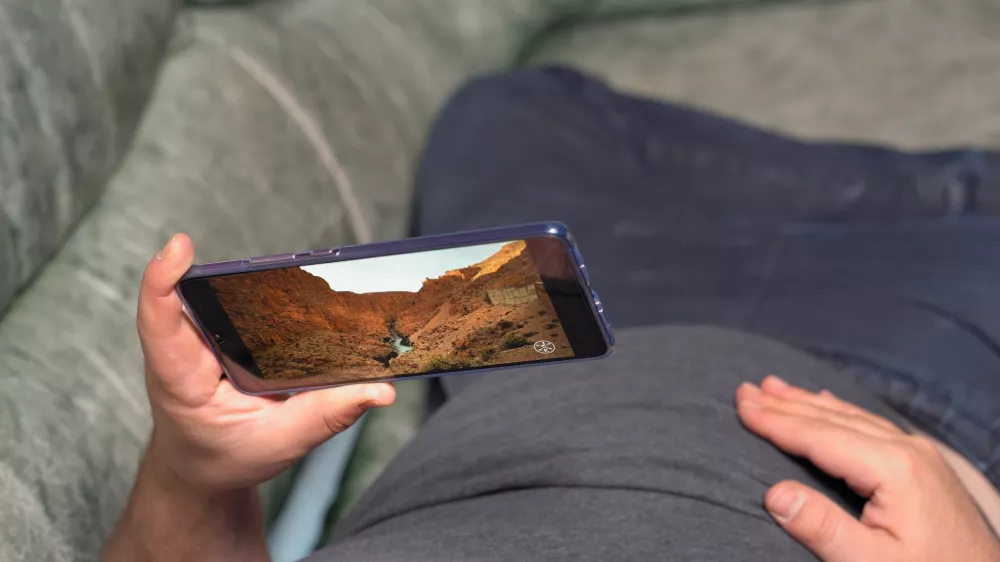 Man lying on couch and watching video about canyon valley in high definition through Huawei Mate 20 X smartphone. Display shows extremely nice and soft image Kyiv, Ukraine 15th of June 2019