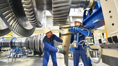 workers assembling and constructing gas turbines in a modern industrial factory