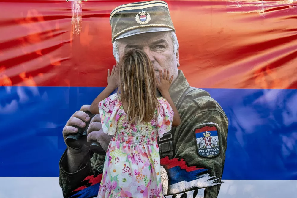 A girl touches a flag with a picture of former Bosnian Serb wartime general Ratko Mladic as mourners gather at the Church of St. Luke, where the body of Mladic lies in state before burial, in Belgrade, Serbia, September 7, 2026. REUTERS/Uros Arsic