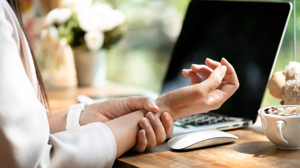 Closeup woman holding her wrist pain from using computer. Office syndrome hand pain by occupational disease.
