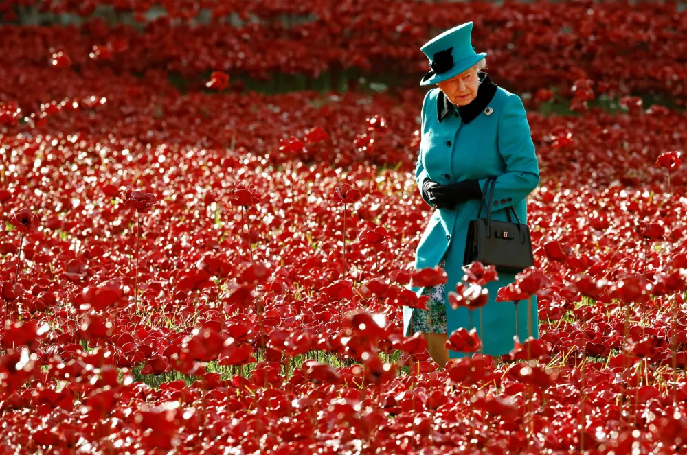 FILE PHOTO: Britain's Queen Elizabeth walks through a field of ceramic poppies that form part of the art installation "Blood Swept Lands and Seas of Red", at the Tower of London in London October 16, 2014. REUTERS/Luke MacGregor/File Photo