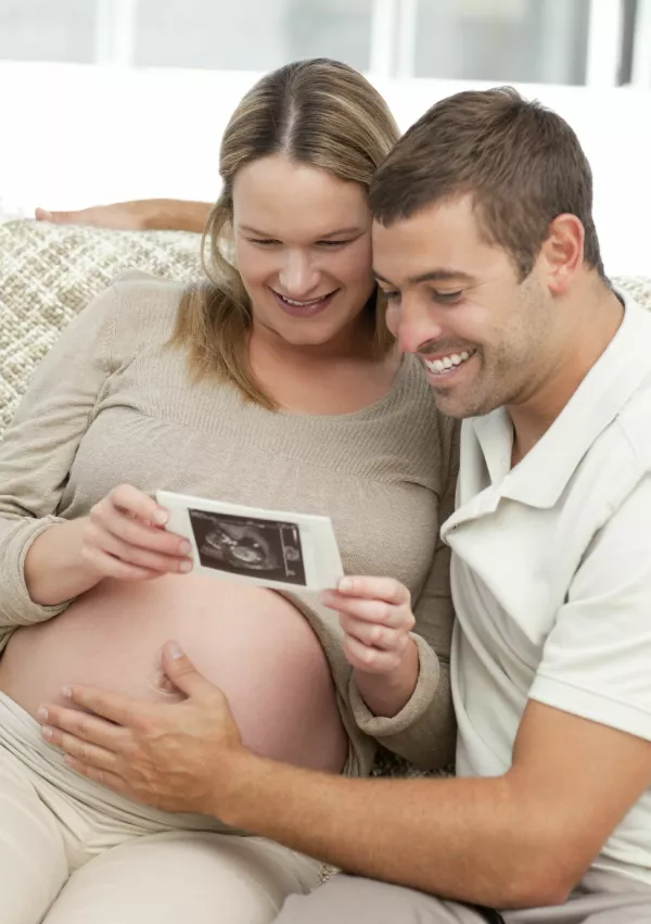 Lovely couple looking at an echography while relaxing in the living-room / Foto: Istock
