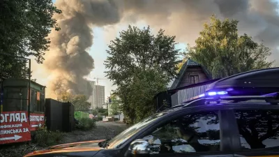 An emergency service vehicle drives by the site of a Russian drone strike as smoke rises in the background, amid Russia's attack on Ukraine, in Kyiv, Ukraine, September 16, 2026. REUTERS/Alina Smutko