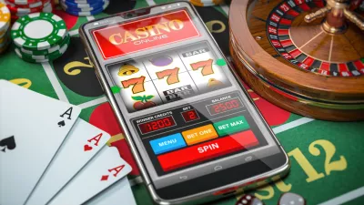 Casino online. Smartphone or mobile phone, slot machine, dice, cards and roulette on a green table in casino. 3d illustration / Foto: Bet_noire
