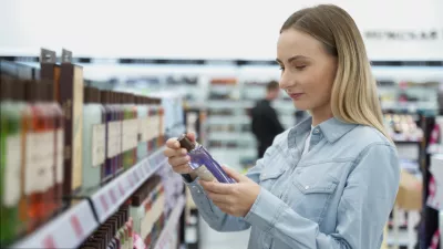 Shopping - young woman holding bottle of shampoo in supermarket. / Foto: Viktoria Korobova Getty Images