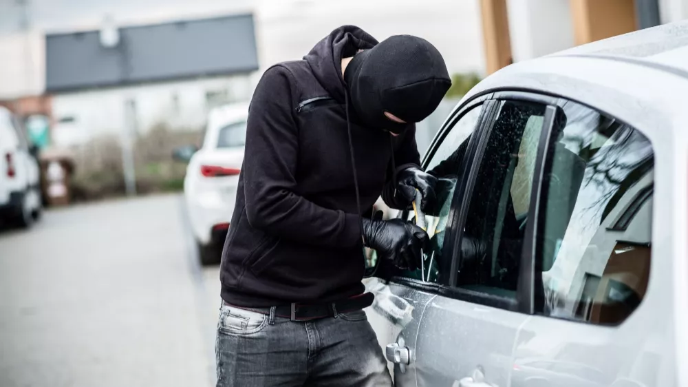 Car thief trying to break into a car with a screwdriver. Car thief, car theft. / Foto: Djedzura