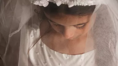 A young girl preparing for her holy communion, photographed with her veil covering her face and looking down