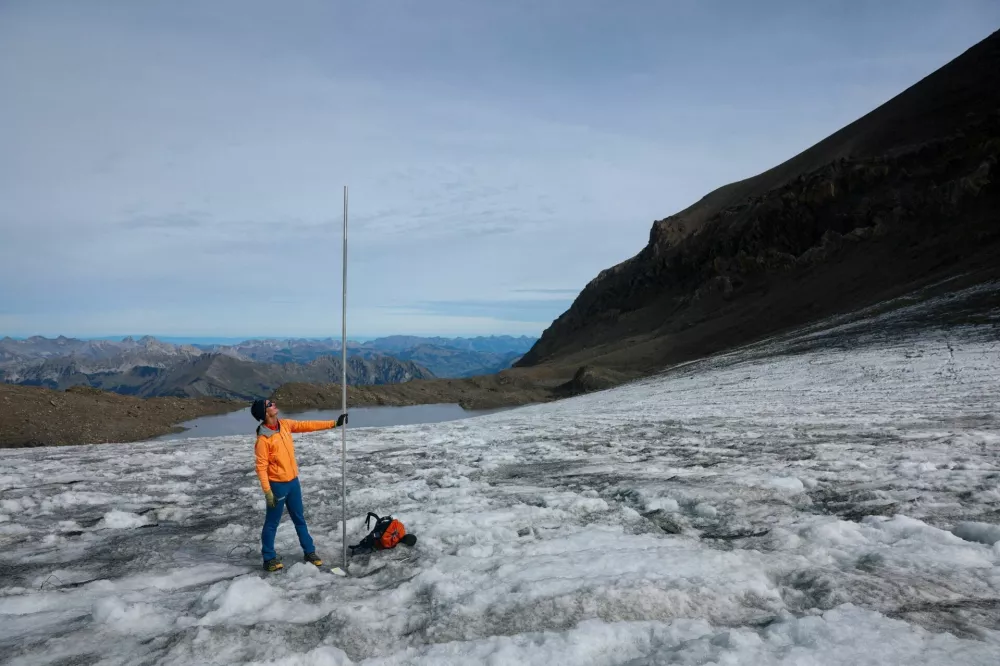 Glaciologist at ETH Zurich and head of Glacier Monitoring in Switzerland (GLAMOS) Matthias Huss holds a pole that indicates four metres of ice lost over the past year on the Scex Rouge glacier amid climate change at Glacier 3000 in Les Diablerets, Switzerland, September 24, 2026. REUTERS/Denis Balibouse   TPX IMAGES OF THE DAY
