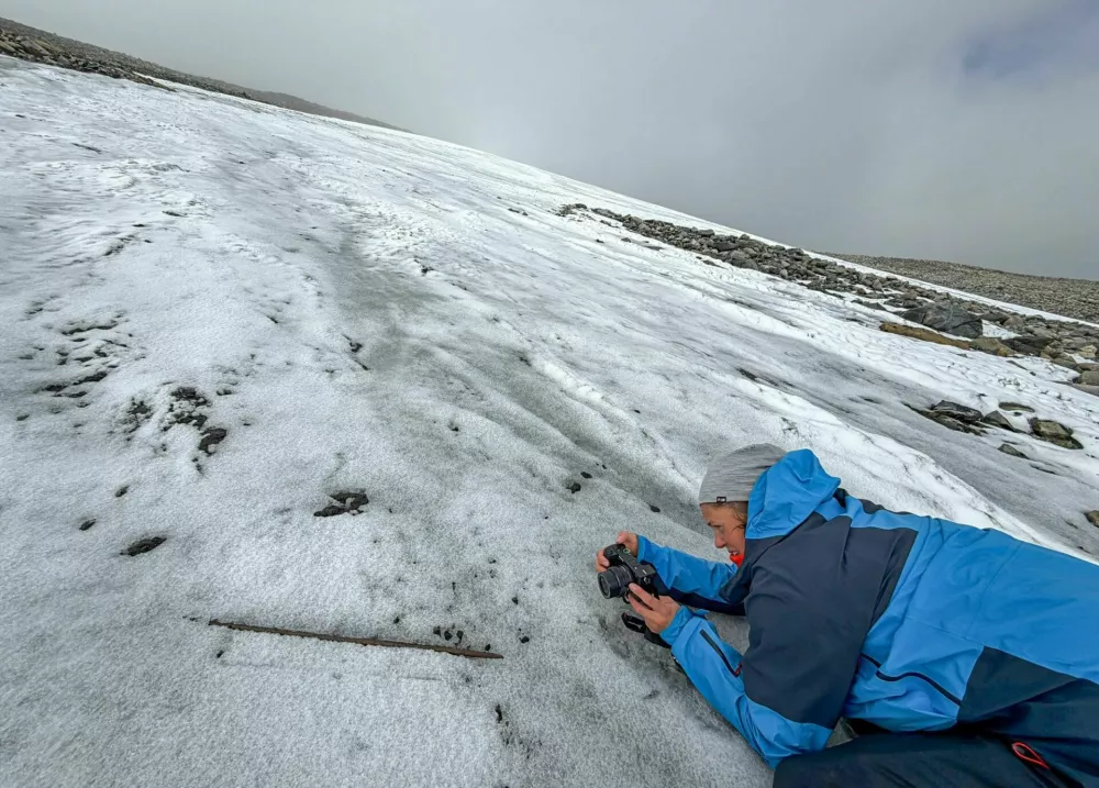 Najprej fotografija, potem re&scaron;evanje. Arheologinja &Aring;sa Rommetveit Celius dokumentira približno 1000 let star lesen držaj pu&scaron;čice na mestu, kjer ga je izpustil taleči se led. Foto: May-Tove Smiseth/Innlandet fylkeskommune/Secrets of the Ice / Foto: Foto: May-tove Smiseth/innlandet Fylkeskommune/secrets Of The Ice