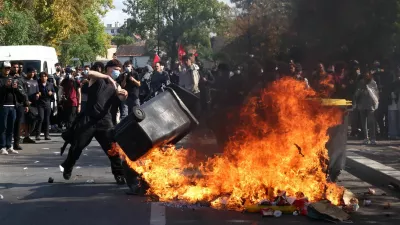 A masked protester throws a garbage bin into a fire set up by high school and university students in a street amid clashes with French riot police during a student protest to demand the hiring of substitute teachers, increased resources and better learning conditions, and to support the ongoing high-school student movement in the Seine-Saint-Denis department, in Saint-Denis near Paris, France, October 1, 2026. REUTERS/Abdul Saboor