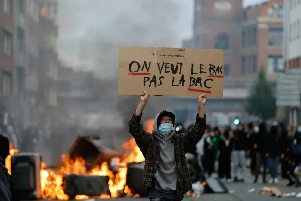 A students holds a board reading, "we want BAC (High School Diploma) Not the BAC (Anti-criminality units)" during a protest to demand more resources at school, in Lille, France, Thursday, Oct. 1, 2026. (AP Photo/Jean-Francois Badias)