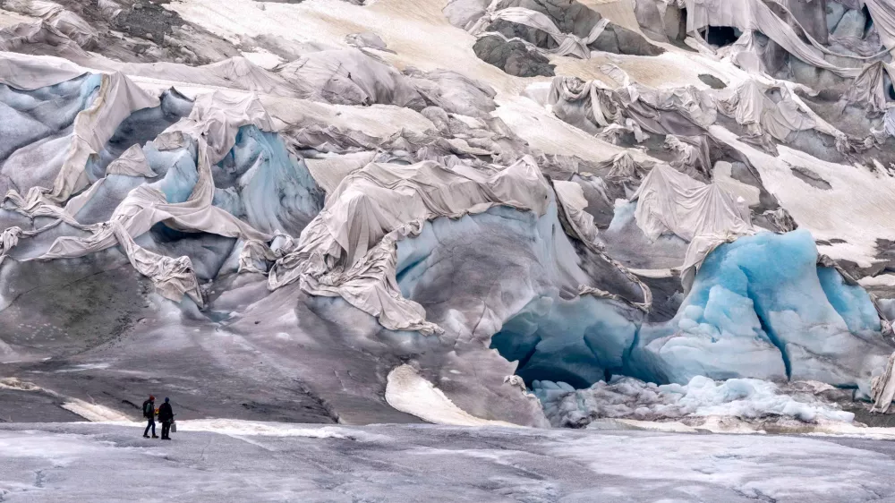 FILE &mdash; Team members of ETH (Swiss Federal Institute of Technology) glaciologist and head of the Swiss measurement network 'Glamos', Matthias Huss, arrive at the Rhone Glacier partially covered near Goms, Switzerland, June 16, 2023. (AP Photo/Matthias Schrader, File) / Foto: Matthias Schrader