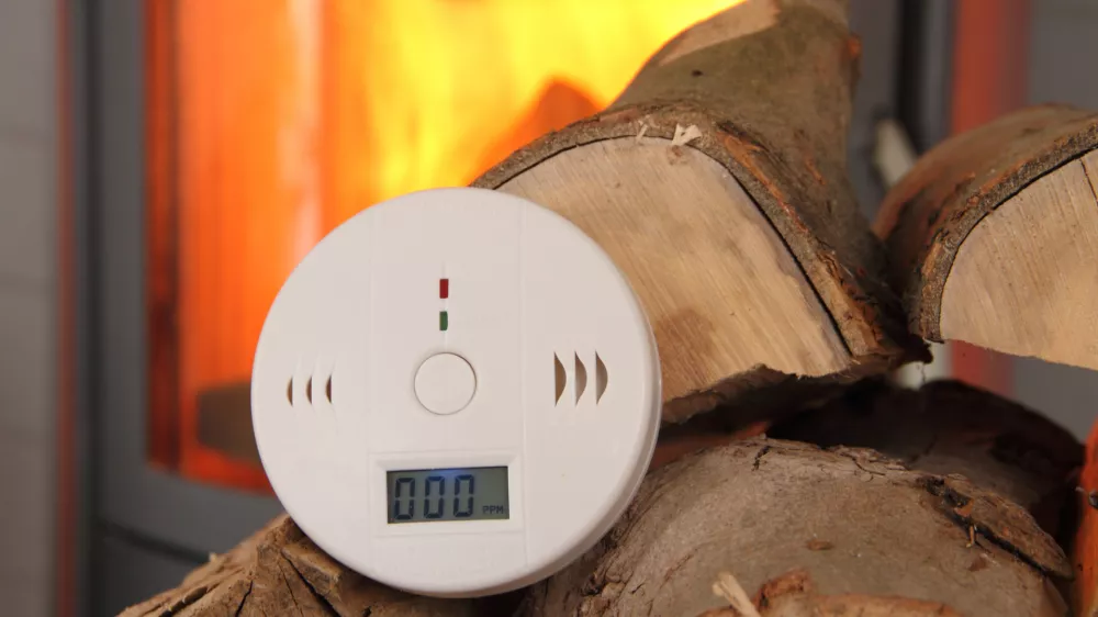 a CO detector in front of a burning fireplace