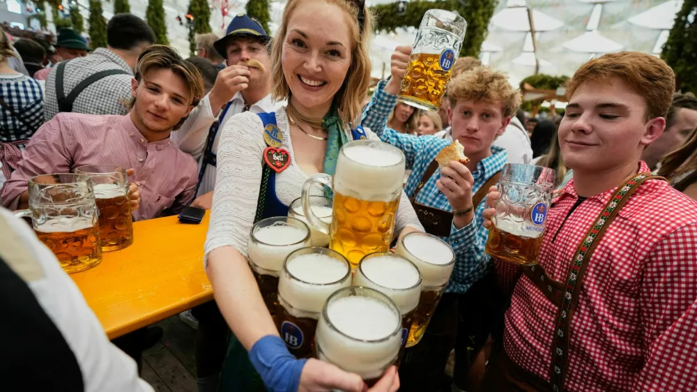 A waitress carries beer mugs after the opening of the 191st Oktoberfest beer festival in Munich, Germany, Saturday, Sept.19, 2026. (AP Photo/Matthias Schrader)