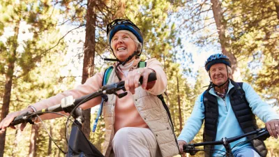 Senior couple mountain biking on a forest trail, low angle