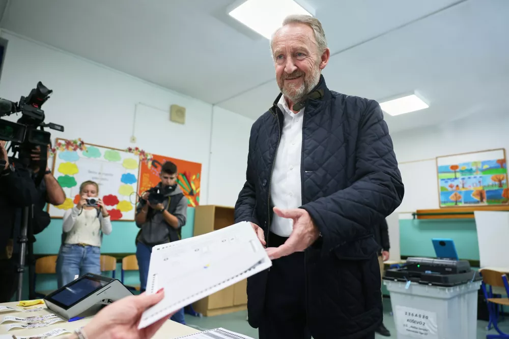 Bakir Izetbegovic of the Party of Democratic Action (SDA), a candidate for the presidency, receives his ballot from an official during the general election in Sarajevo, Bosnia, Sunday, Oct. 4, 2026. (AP Photo/Armin Durgut)
