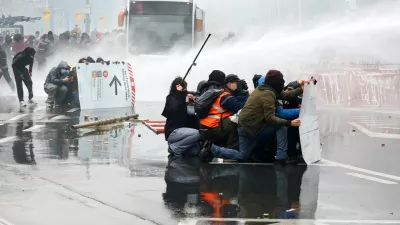 Demonstrators try to get cover from police water cannons as student protesters join a nationwide strike against the Belgian government's austerity measures and budget cuts, in Brussels, Belgium, October 9, 2026. REUTERS/Yves Herman