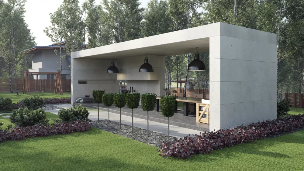 A modern concrete outdoor pavilion featuring a dining area with a long table and kitchen. The structure is surrounded by a green lawn and trees. 3D rendering