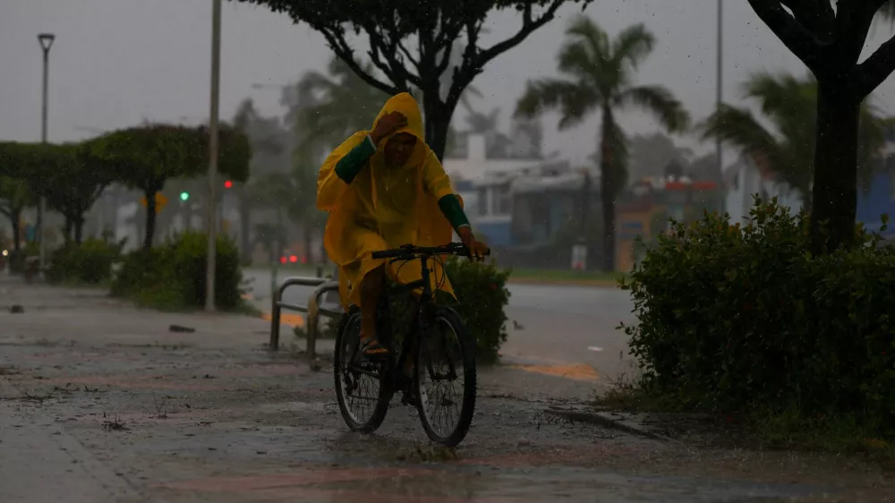 A man rides a bicycle as Hurricane Simon approaches Mexico's Pacific coast, bringing heavy rain and strong winds to Manzanillo, Mexico, October 11, 2026. REUTERS/Daniel Becerril