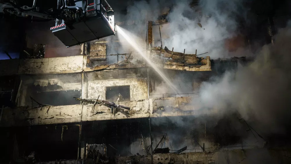 A rescue worker puts out a fire of a multi-story residential building damaged in a Russian missile strike on Kyiv, Ukraine, Wednesday, Oct. 14, 2026. (AP Photo/Evgeniy Maloletka)