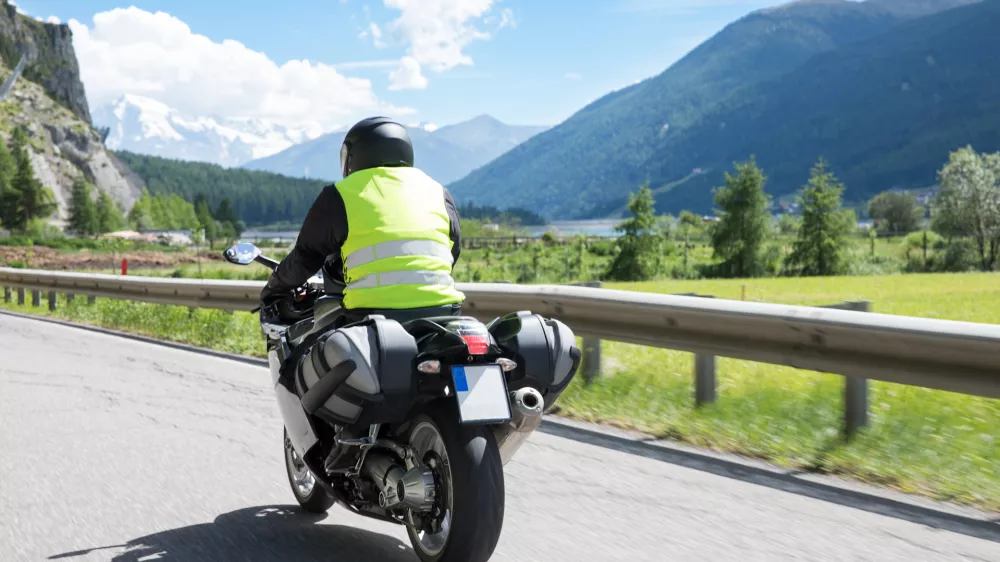 Motorbiker is riding his motorcycle on winding roads through the mountains in the summer sun