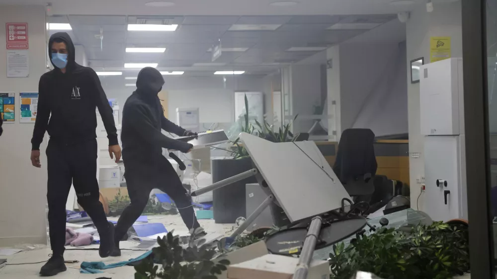 Hooded protesters vandalize a bank during clashes in Tirana, Albania, Wednesday, Oct. 14, 2026, as students joined the Flamingo anti-government movement. (AP Photo/Hameraldi Agolli)