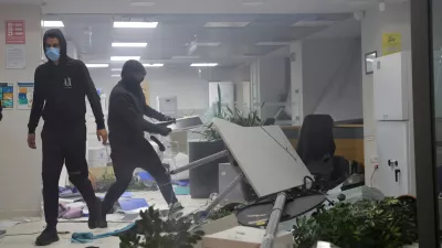 Hooded protesters vandalize a bank during clashes in Tirana, Albania, Wednesday, Oct. 14, 2026, as students joined the Flamingo anti-government movement. (AP Photo/Hameraldi Agolli)