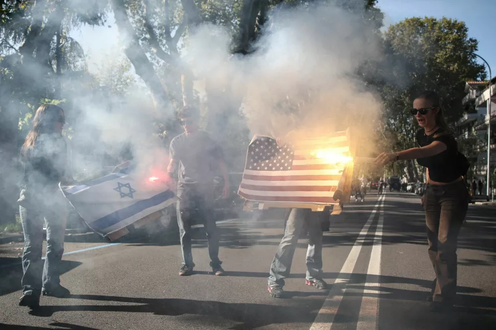 Demonstrators set fire to a U.S. flag and an Israeli flag during a student protest in Rome, Italy, October 16, 2026. REUTERS/Francesco Fotia