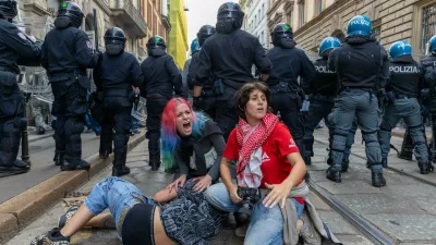 Demonstrators get shelter behind the police after clashes occurred during a protest against the high cost of living, in Milan, Italy, Saturday Oct. 17, 2026. (Stefano Porta/LaPresse via AP)