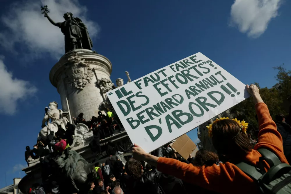 A protester holds a placard reading "Efforts must be made. Starting with Bernard Arnault" near the Marianne statue of the Place de la Republique during a demonstration against the cost of living and rising fuel prices in Paris as part of nationwide protests called by the "Yellow Vests" movement, joined by French high school and university students, teachers and parents demanding better school conditions and government action, as well as labour unions, workers, farmers and retirees, France, October 17, 2026. REUTERS/Stephanie Lecocq&nbsp;   TPX IMAGES OF THE DAY