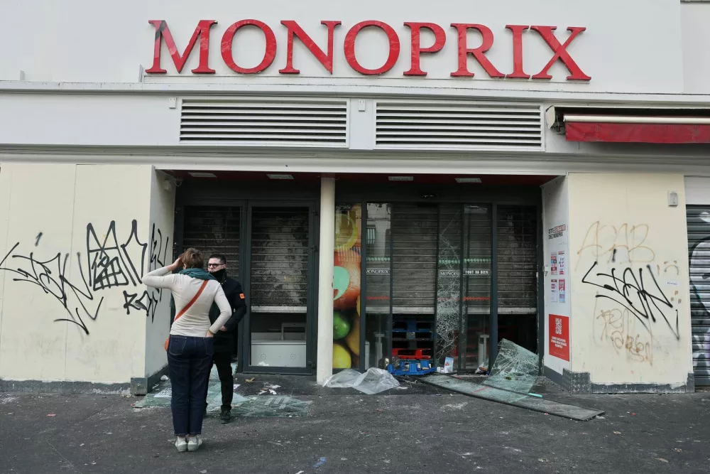 A member of security speaks to a person outside a vandalised Monoprix store, the day after clashes during a national day of demonstrations against the cost of living and rising fuel prices, in Paris, France, October 18, 2026. REUTERS/Stephanie Lecocq