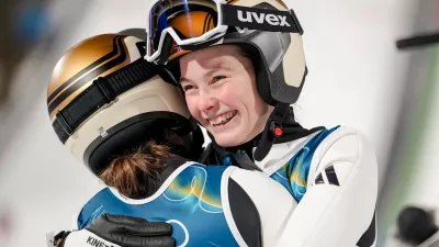 Silje Opseth, of Norway, right, hugs gold medalist Anna Odine Stroem, also of Norway, after the ski jumping women's large hill individual at the 2026 Winter Olympics, in Predazzo, Italy, Sunday, Feb. 15, 2026. (AP Photo/Matthias Schrader)