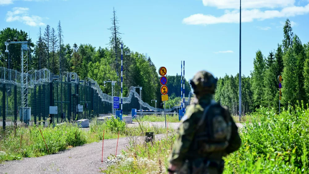 An officer from a special unit of the Finnish Border Guard stands in front of the border fence at a closed border crossing on the Finnish-Russian border.