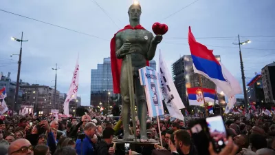 People hold a replica of the Serbian capital landmark The Victor or Pobednik statue during the final "Student List – Students Win" rally ahead of a parliamentary election in Belgrade, Serbia, Thursday, Oct. 22, 2026. (AP Photo/Petr David Josek)