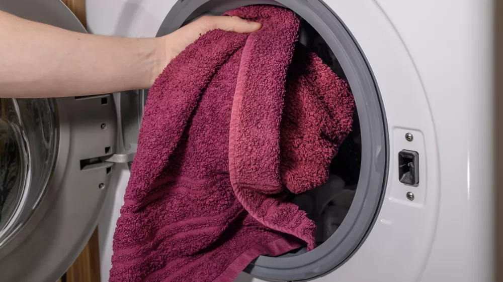 Putting a dirty towel into the washing machine close up