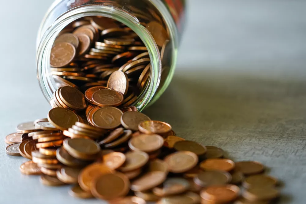 Spilled Glass Jar Full of Copper Euro Cents on a Table Symbolizing Savings, Budgeting, and the Value of Small Change