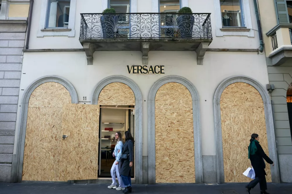 People walk by a boarded-up Versace shop, ahead of a protest called by the October 17 Movement against the rising cost of living, in Milan, Italy, October 24, 2026. REUTERS/Yara Nardi REFILE - CORRECTING FASHION HOUSE FROM "GUCCI" TO "VERSACE".