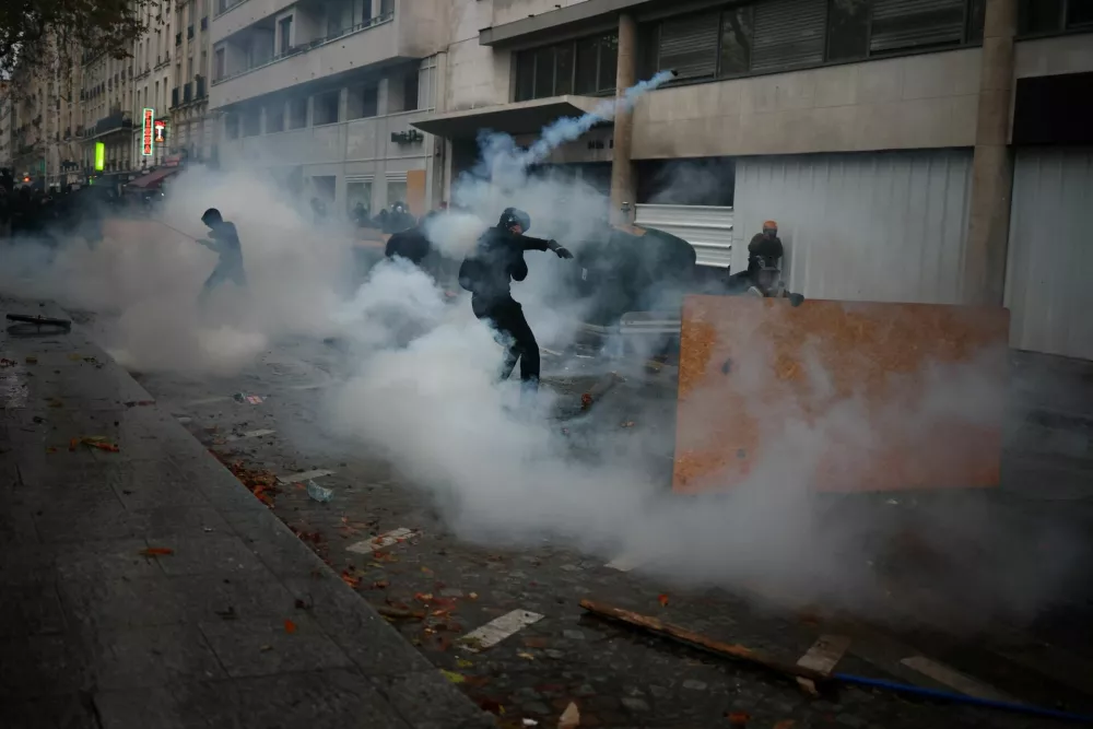 Masked protesters take cover behind a plywood board amid clashes and tear gas during a demonstration organised by labour unions in Paris as part of nationwide protests called by the "Yellow Vests" movement joined by French high school and university students against the cost of living and rising fuel prices, in France, October 24, 2026. REUTERS/Pedro Nunes