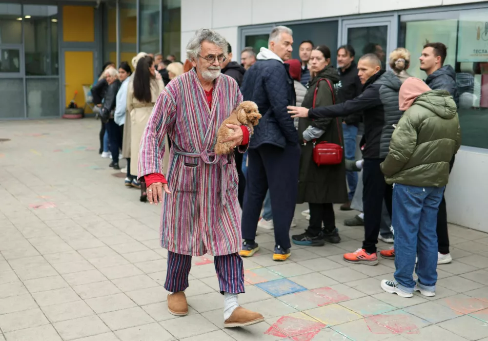 A man, carrying his dog, leaves a polling station after casting his vote as people queue to vote during the parliamentary election in Belgrade, Serbia, October 25, 2026. REUTERS/Marko Djurica   TPX IMAGES OF THE DAY