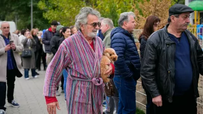 A man holds a dog while arriving at a polling station to vote in a parliamentary election in Belgrade, Serbia, Sunday, Oct. 25, 2026. (AP Photo/Petr David Josek)