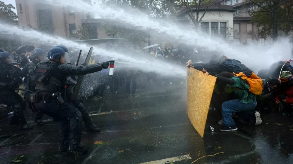 FILE PHOTO: Protesters take cover behind a plywood board as French riot police and gendarmes use a water canon amid clashes during an authorised demonstration organised by labour unions in Paris as part of nationwide protests called by the "Yellow Vests" movement joined by French high school and university students against the cost of living and rising fuel prices, in France, October 24, 2026. REUTERS/Hannah McKay   TPX IMAGES OF THE DAY/File Photo